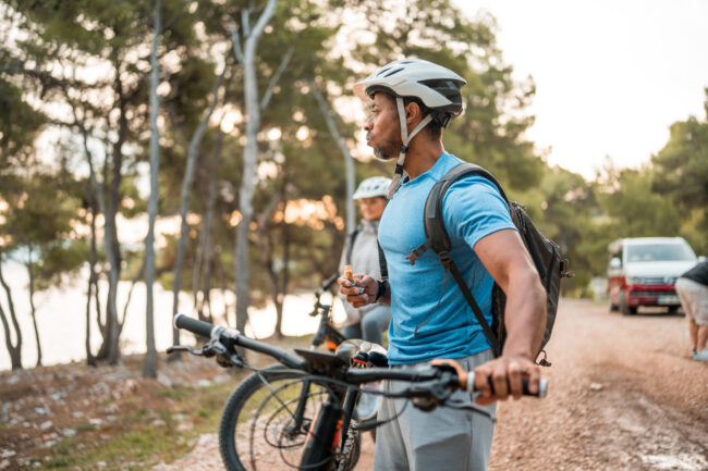 Active Black Cyclist Refuels with Snack During Sunrise Ride